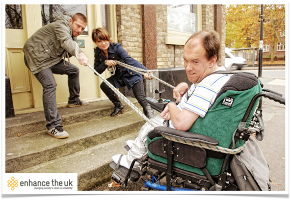 a wheelchair user being 'helped' up some stairs
