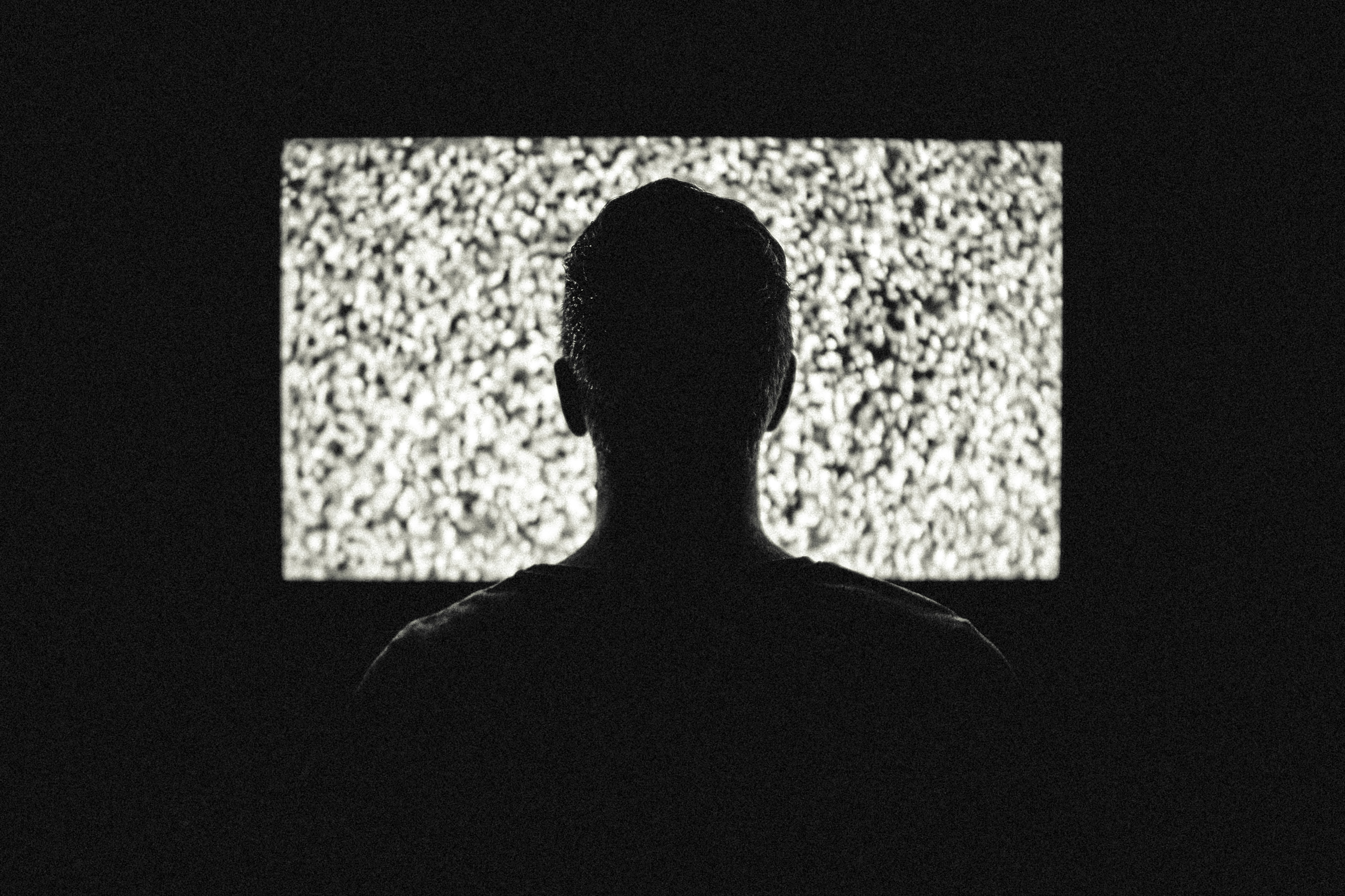 A man starring at a TV in a dark room