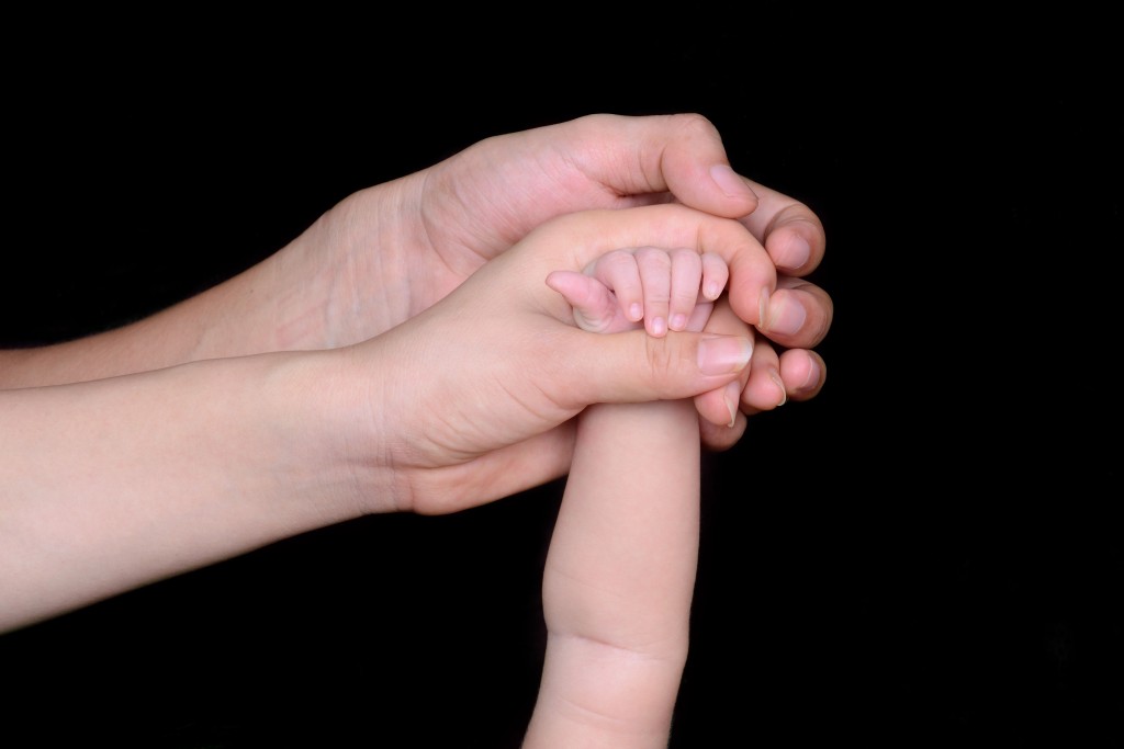 Parents interlocking their hands together with their child's
