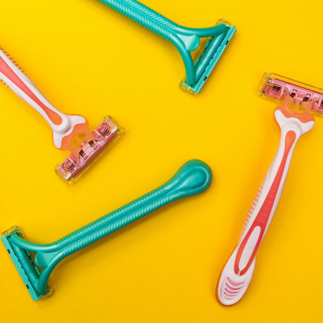 Green and pink ladies razors on a yellow background.